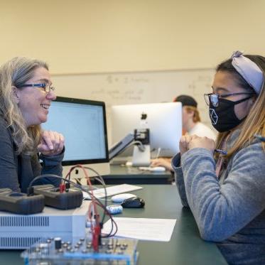 Physics instructor talking with a student in lab