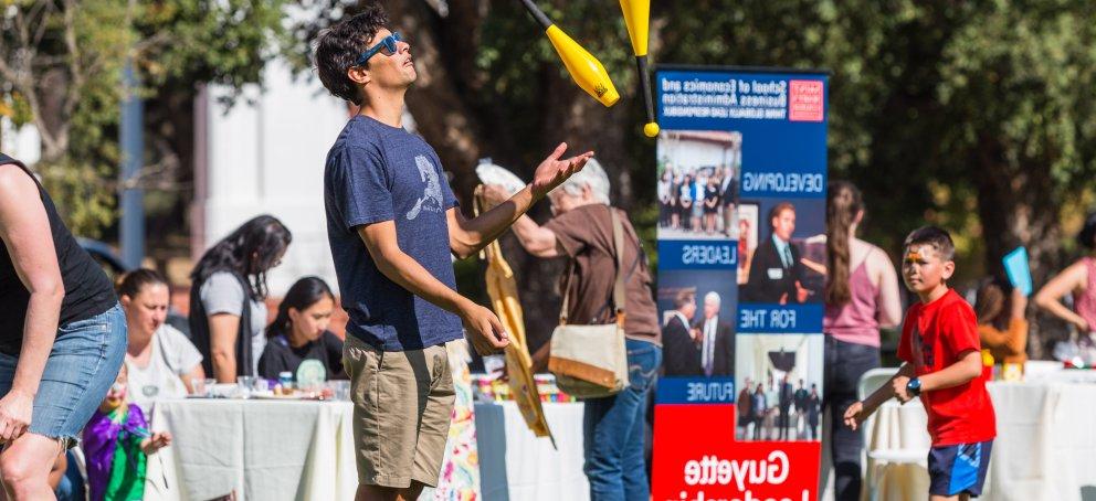 a student is on the lawn juggling clubs at a school event