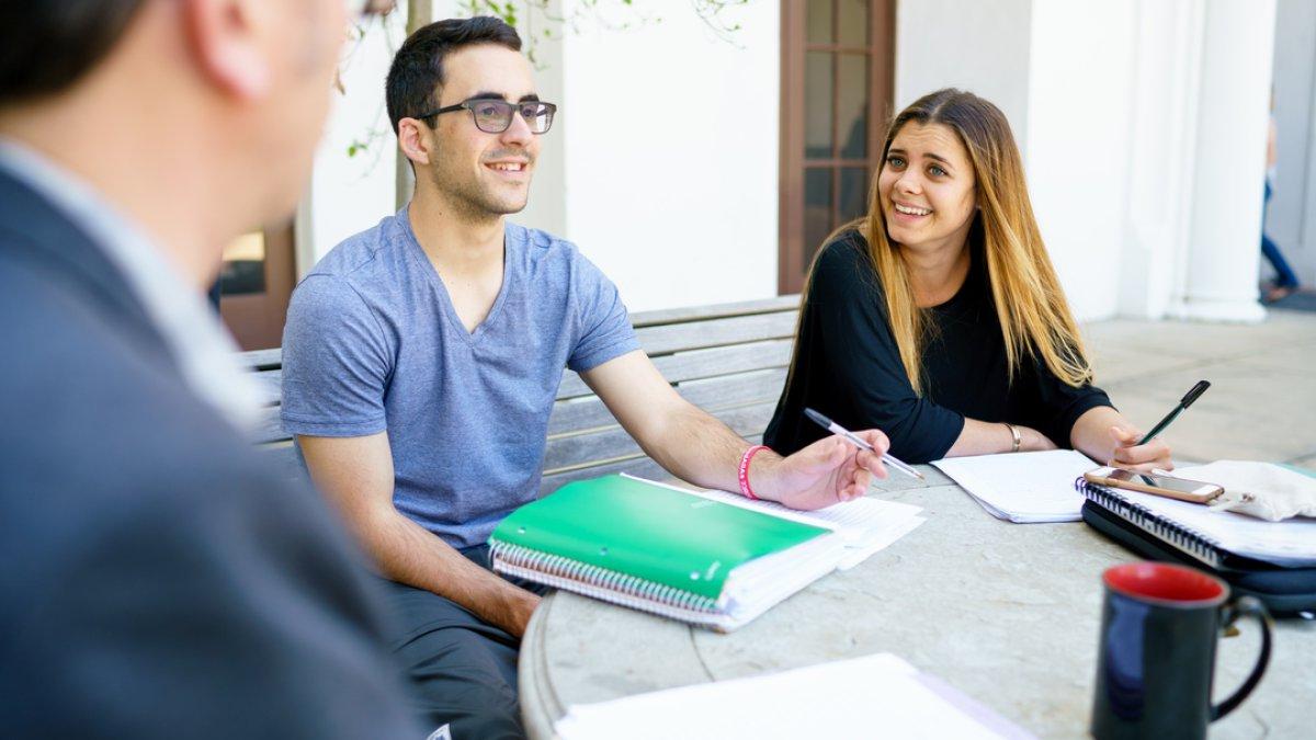 Student at the writing center meeting at a table outside on Saint Mary's campus