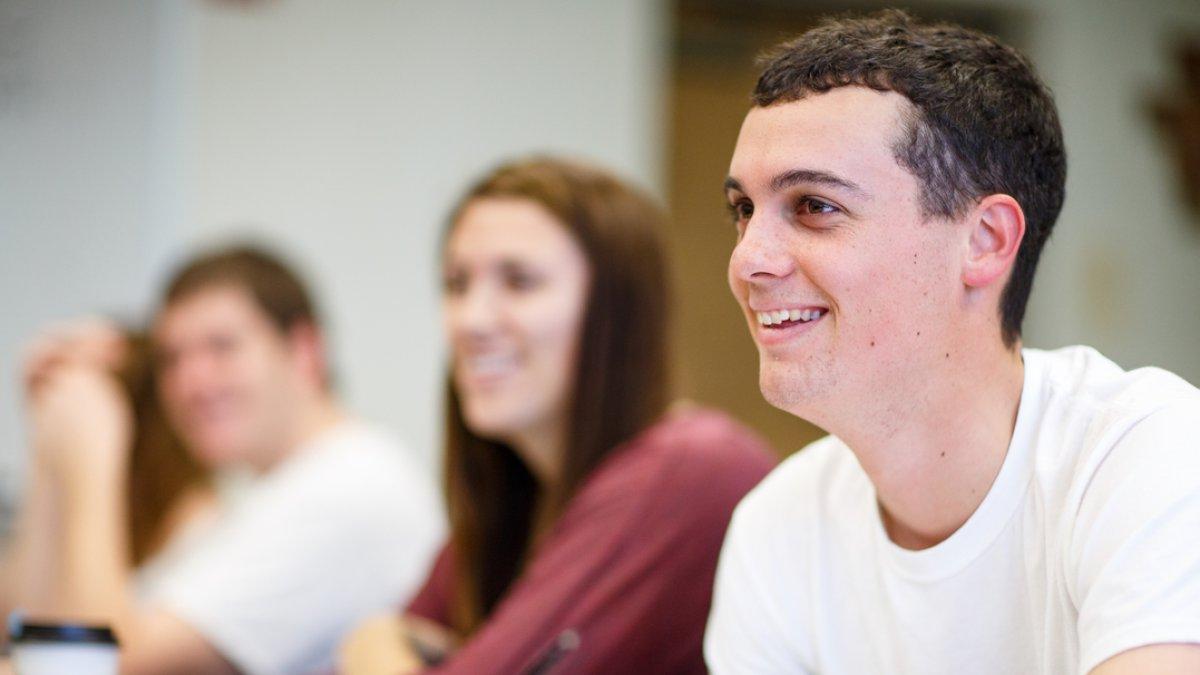 Students are sitting at their desks in class looking up and smiling